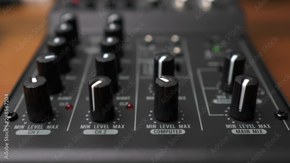 Poster hand rotating computer volume knob on professional mixing console, static