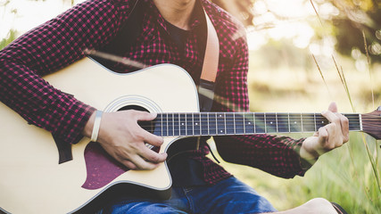 Fototapeta premium Music in nature, People playing guitar in rural grasslands, Close-up