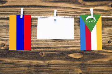 Hanging flags of Armenia and Comoros attached to rope with clothes pins with copy space on white...