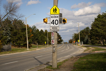 School zone ahead speed limit when lights flashing.Street attention restriction sight and streetlight.Yellow traffic light on theconcrete pillar with the street view and road on the background.