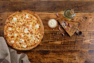 Pizza with salmon and cheese on a wooden background. Ingredients for the sauce. Close-up. The...