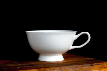 Coffee cup on old wooden table in dark background.