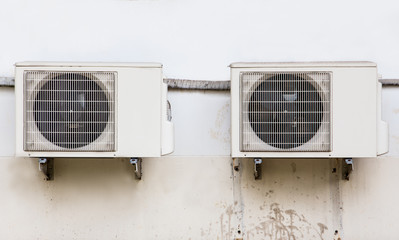 Compressors of air conditioning fixed to a dirty wall background.