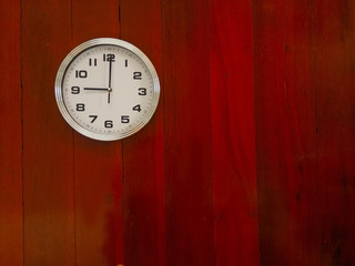 wall clock at wooden background texture, read at 9 o'clock.