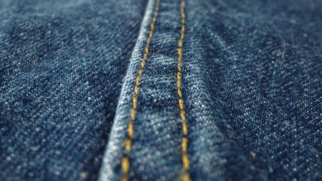 Extreme detailed of blue denim jeans cloth texture in macro dolly shot over the cloth surface. Flow view of clothing material. Textile abstract background. Vintage fashion apparel industry concept.