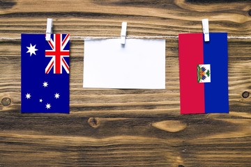Hanging flags of Australia and Haiti attached to rope with clothes pins with copy space on white...