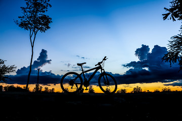 Naklejka premium Silhouette of bicycle at the lake at sunset time in summer.