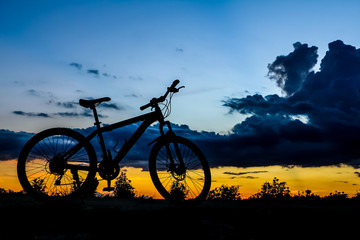 Silhouette of bicycle at the lake at sunset time in summer.