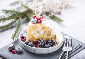 Christmas cake with cranberries and Christmas decorations on a light background.