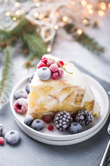 Christmas cake with cranberries and Christmas decorations on a light background.