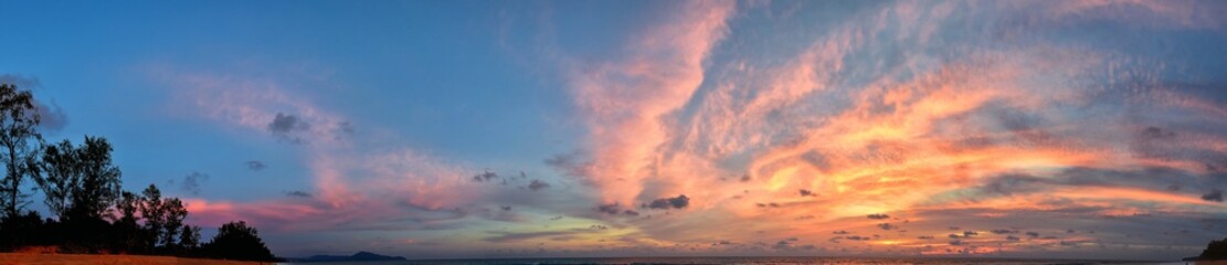 Phuket beach sunset, colorful cloudy twilight sky reflecting on the sand gazing at the Indian Ocean, Thailand, Asia.