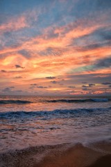 Phuket beach sunset, colorful cloudy twilight sky reflecting on the sand gazing at the Indian Ocean, Thailand, Asia.