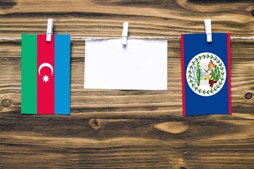 Hanging flags of Azerbaijan and Belize attached to rope with clothes pins with copy space on white note paper on wooden background.Diplomatic relations between countries.
