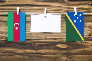 Hanging flags of Azerbaijan and Solomon Islands attached to rope with clothes pins with copy space...