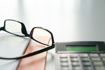 Reading glass on table with file and calculator. Business or work concept.