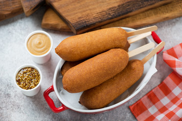 Corn dogs served in a bowl over beige stone background, high angle view, studio shot