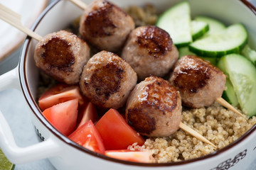 Close-up of meatball skewers with quinoa and fresh vegetables, selective focus