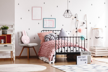 Cozy pastel pink woolen blanket on single industrial bed in scandinavian bedroom interior for...