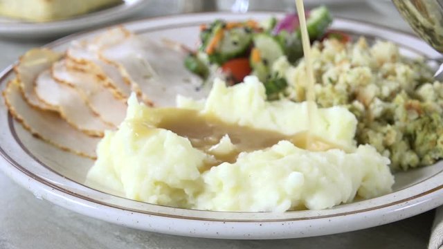 Pouring gravy over mashed potatoes with a turkey dinner, slow motion