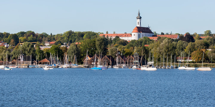LAKE AMMERSEE, BAVARIA / GERMANY - Sept 29, 2019: Panorama view on the town of Diessen, captured from a boat. The church in the background is the Marienmünster (catholic abbey). Sailboats anchoring.