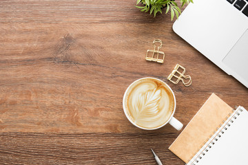 Wood minimalist office desk table with laptop computer, cup of cafe lattee coffee and office supplies. Top view with copy space, flat lay, minimal style.