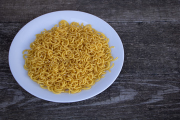 Un-cooked pasta in a plate on wooden background