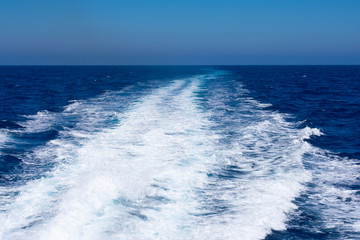 Background made of clear sea water surface with kelvou jet, bubbles and waves on water surface with copy space