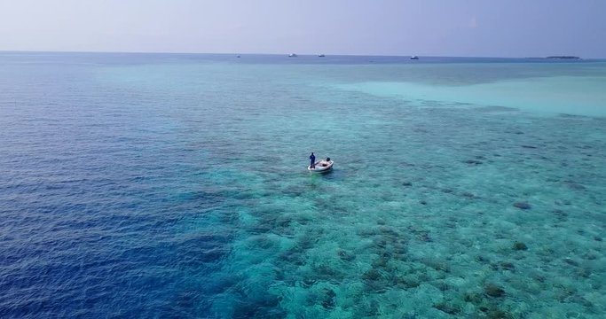 Boay in the middle of the ocean in Fiji - fishing and exploring shallow reef - crystal clear waters - Aerial Shot 4K
