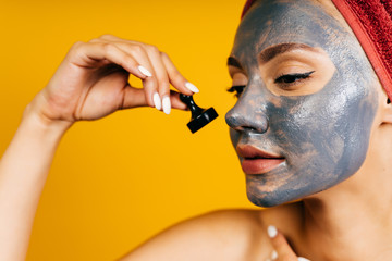 girl with a black mask on her face with looks at a chess piece