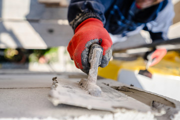 Construction worker plastering a wall with trowel cement mortar applying adhesive cement on the...