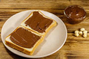 Two slices of bread with delicious chocolate hazelnut spread on wooden table
