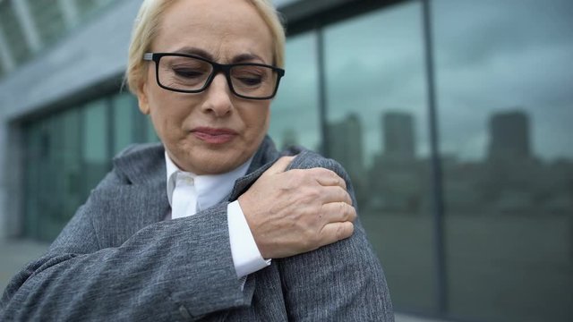 Female office worker in her 50s suddenly feeling pain in shoulder, sprain result