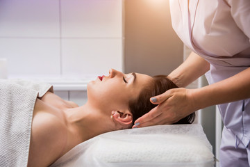 Fototapeta na wymiar Beautiful young woman enjoying head massage in spa salon. Cosmetology