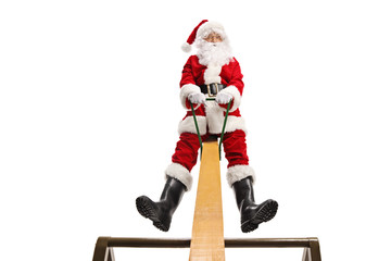 Cheerful Santa Claus playing on a seesaw