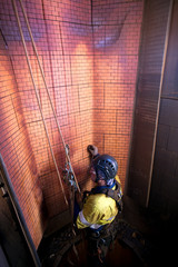 Industry rope access NDT inspector wearing full body safety harness hardhat hanging in full arrest position commencing wall thickness measurement inspection services, construction mine site Perth