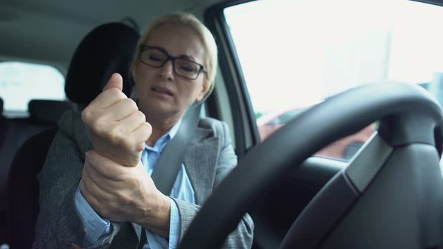 Woman driver feeling pain in wrist holding steering wheel, spasm, arthritis