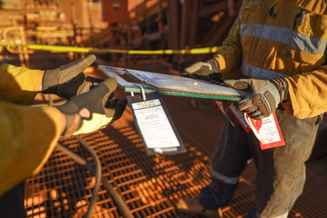 Senior miner supervisor holding and hand over isolation safety control lock box permit to work board to workmate during shift changing on two weeks shut down operation construction site Perth - obrazy, fototapety, plakaty