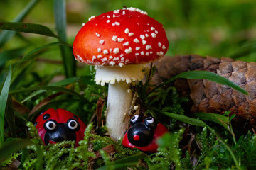Fly agaric closeup with figures of ladybug beneath