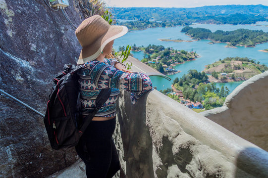 Vista trasera de mujer turista contemplando la naturaleza en Guatape Colombia desde la cima de la piedra del peñol