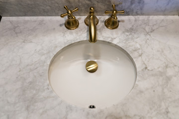 Sink made of expensive marble stone. Golden design of faucet and taps