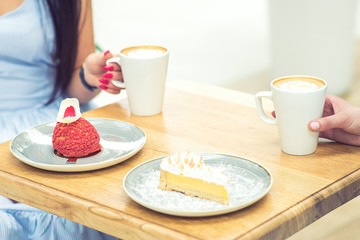 Two young women meet at the bar for cappuccino with desserts and to chat. Two women having snack in cafe.