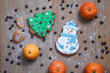 Beautiful gingerbread cookie in the form of a snowman and a Christmas tree on a background of a wooden texture with coffee grains. Winter christmas theme