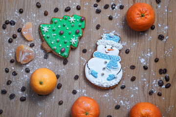 Beautiful gingerbread cookie in the form of a snowman and a Christmas tree on a background of a wooden texture with coffee grains. Winter christmas theme