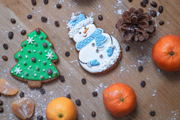 Beautiful gingerbread cookie in the form of a snowman and a Christmas tree on a background of a wooden texture with coffee grains. Winter christmas theme