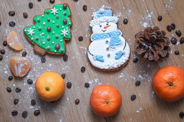 Beautiful gingerbread cookie in the form of a snowman and a Christmas tree on a background of a wooden texture with coffee grains. Winter christmas theme