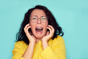 funny shocked face. frames trying eyeglasses. girl holding glasses standing on turquoise background, Concept: poor eyesight.