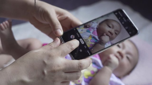 Mom is taking pictures of a baby with a smartphone