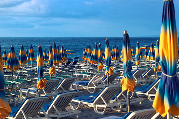 Sea or ocean beach with deck chairs and umbrellas. Mood stormy weather. End of tourist season.