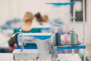 Skeins of thread and sewing machine on background of seamstresses and sewing workshop