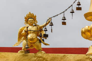 LHASA, TIBET / CHINA - Jul 30, 2017: Golden colored statue holding a string with bells on top of...